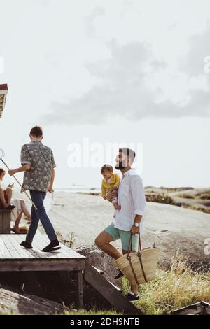 Vista posteriore del ragazzo adolescente con padre e sorella arrampicata gradini della cabina Foto Stock