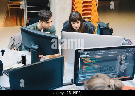 Visualizzazione ad alto angolo dei programmatori di computer che utilizzano il PC desktop AT scrivania da ufficio Foto Stock