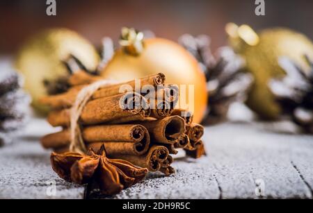 Pacchetto di bastoncini di cannella con stelle di anice sullo sfondo di legno innevato pronto per cucinare panetteria di natale. Decorazioni natalizie. Messa a fuoco selettiva. Foto Stock