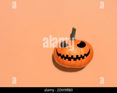 Zucca di Halloween in mano su sfondo arancione. Foto Stock