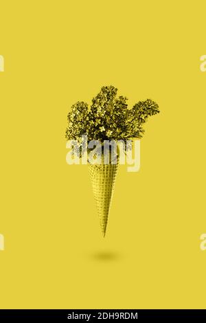 Cono gelato con fiori lilla in 2021 nuovi colori alla moda illuminanti giallo. Cialda con fiori primaverili. Colore dell'anno 2021. Biglietto d'auguri Foto Stock