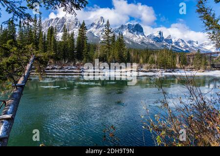 Canmore Engine Bridge nelle prime stagioni invernali giorno di sole mattina. Drift ghiaccio galleggiante sul fiume Bow. Cielo blu chiaro, neve coperto Monte Rundle Foto Stock