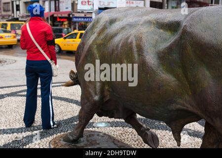Istanbul, Turchia - 18 ottobre 2011 : un momento divertente di quando una giovane donna in tuta rossa stava per essere orlata dalla statua di un toro a Kadikoy, Foto Stock