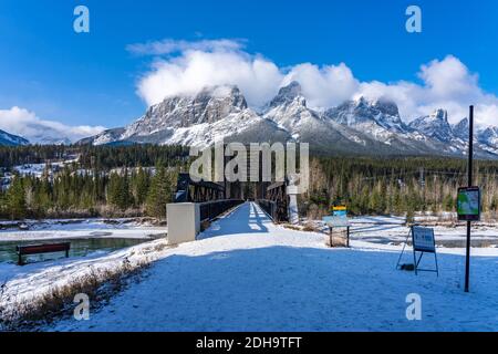 Canmore Engine Bridge nelle prime stagioni invernali giorno di sole mattina. Drift ghiaccio galleggiante sul fiume Bow. Cielo blu chiaro, neve coperto Monte Rundle Foto Stock