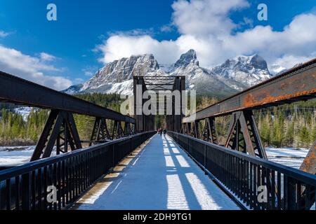 Canmore Engine Bridge nelle prime stagioni invernali giorno di sole mattina. Drift ghiaccio galleggiante sul fiume Bow. Cielo blu chiaro, neve coperto Monte Rundle Foto Stock