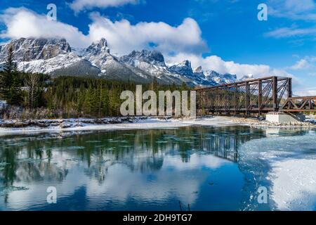 Drift ghiaccio galleggiare sul fiume Bow in prima stagione invernale giorno di sole mattina. Cielo blu chiaro, innevata catena montuosa del Monte Rundle sullo sfondo. Foto Stock