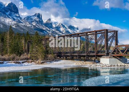 Drift ghiaccio galleggiare sul fiume Bow in prima stagione invernale giorno di sole mattina. Cielo blu chiaro, innevata catena montuosa del Monte Rundle sullo sfondo. Foto Stock