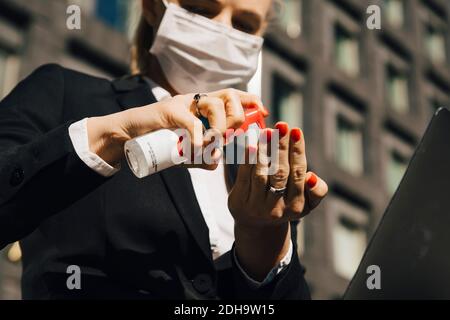 Donna d'affari con maschera facciale con igienizzatore per le mani Foto Stock