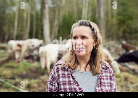 Donna matura che guarda via mentre si sta sul campo Foto Stock