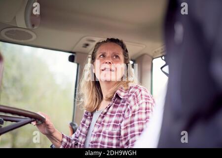 Madre che guarda il figlio mentre è seduto sul trattore Foto Stock