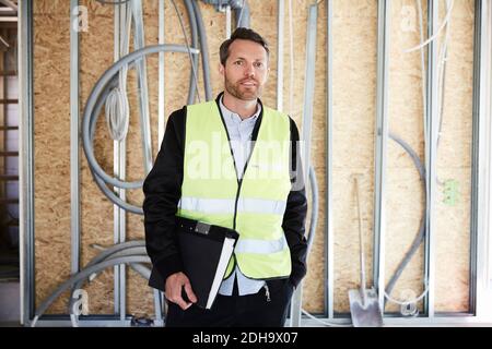 Architetto maturo con lima in piedi in cantiere sul sole giorno Foto Stock