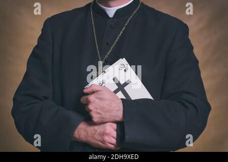 Le mani del sacerdote cattolico che reggono la bibbia Santa Foto Stock