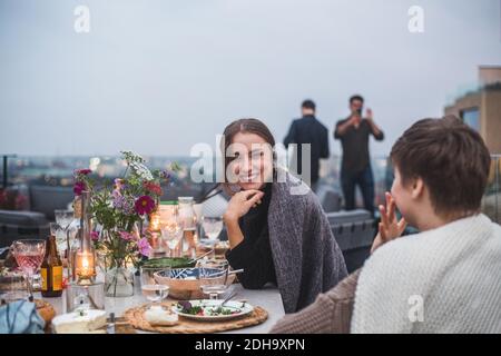 Sorridendo amici che parlano mentre si siede sulla terrazza durante il sociale raccolta Foto Stock