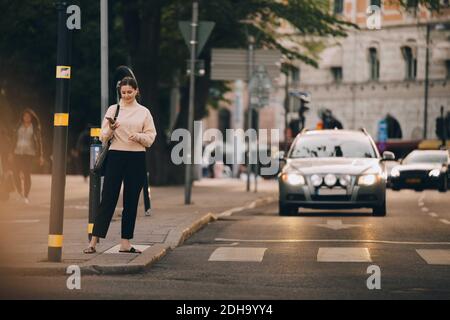 Donna alla moda che usa il telefono cellulare mentre si trova in città Foto Stock