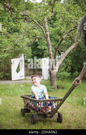 Nonna che tira il carrello con il ragazzo sorridente al cortile posteriore Foto Stock