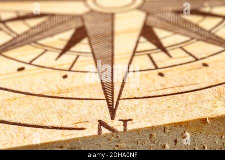 Macrofotografia di una bussola dipinta su una tavola di legno, piccola profondità di campo, vicino alla direzione nord. Foto Stock