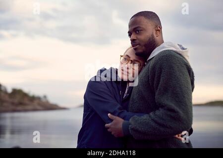 Coppia in piedi sulla spiaggia contro il cielo durante il tramonto Foto Stock