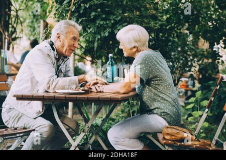 Coppia senior che tiene le mani mentre si siede al ristorante città Foto Stock