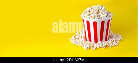 Scatola a righe con popcorn su sfondo giallo Foto Stock