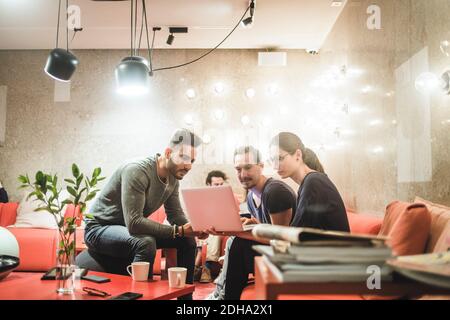 Colleghi di sesso maschile e femminile che lavorano su un computer portatile mentre si siedono ufficio creativo Foto Stock