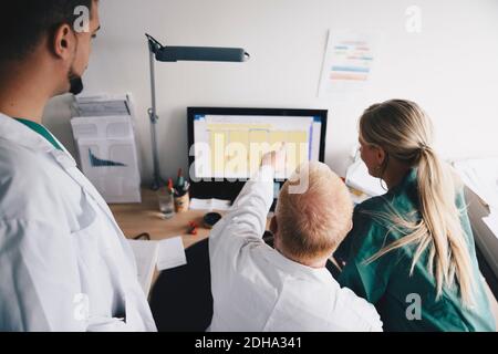Vista ad alto angolo dell'infermiera femminile e dei medici di sesso maschile che discutono sul computer in ufficio Foto Stock