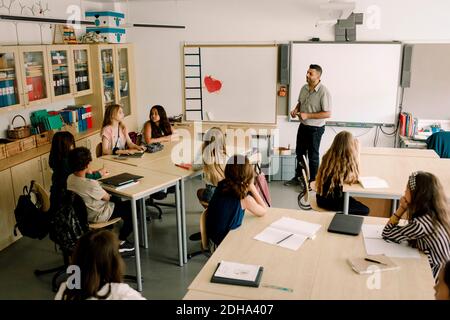 Insegnante maschile che insegna agli studenti in classe Foto Stock