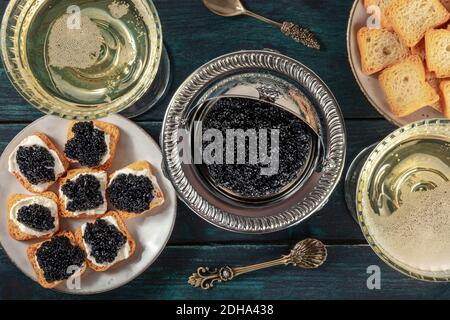 Caviale nero con champagne in calici coupé vintage, con toast, un piatto, top shot Foto Stock