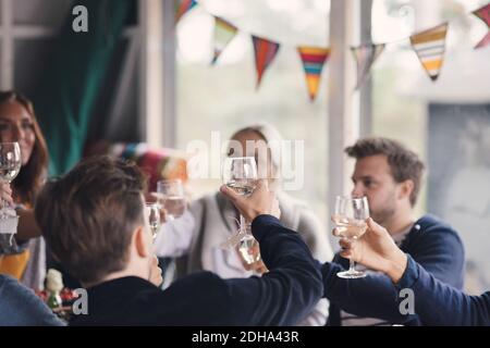 I giovani amici tostano il vino mentre si siedono a casa Foto Stock