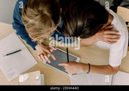 Visualizzazione ad alto angolo degli studenti di sesso maschile che utilizzano il tablet digitale in in aula Foto Stock