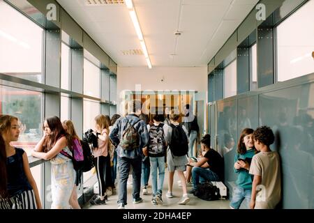 Vista posteriore degli studenti che camminano nel corridoio scolastico durante la pausa Foto Stock