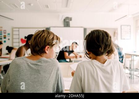 Vista posteriore degli studenti di sesso maschile che studiano in classe Foto Stock