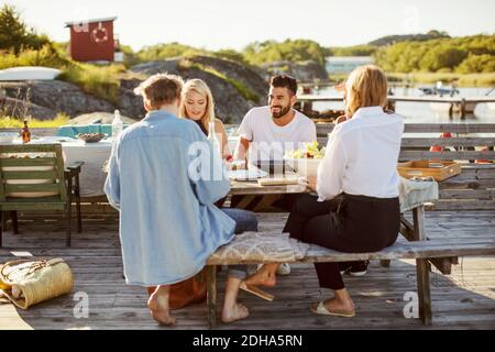 I giovani amici multietnici gusteranno il pranzo estivo al porto Foto Stock