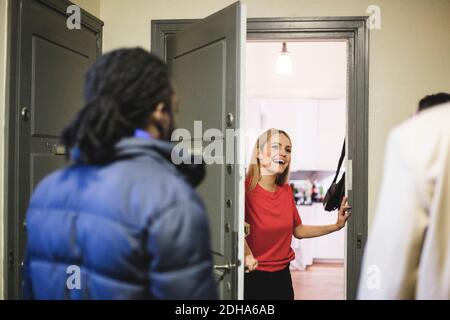 Donna allegra che saluta gli amici mentre si trova alla porta Foto Stock