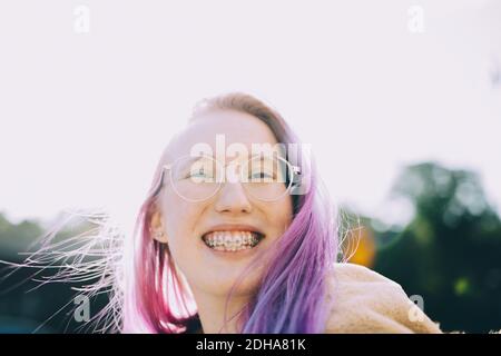 Ritratto di sorridente adolescente in piedi contro cielo chiaro Foto Stock