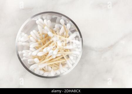 Una foto in alto di bastoncini di cotone di bambù in un bicchiere vasetto su una superficie di marmo Foto Stock