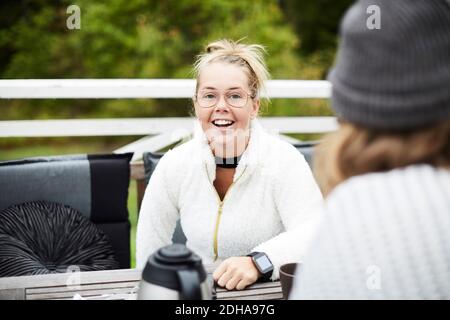 Sorridente donna disabile che guarda il custode maschile seduto al tavolo in cortile Foto Stock