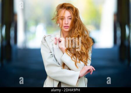 Elegante giovane donna dai capelli rossi che cammina per la strada in autunno. Concetto di bellezza naturale. Foto Stock