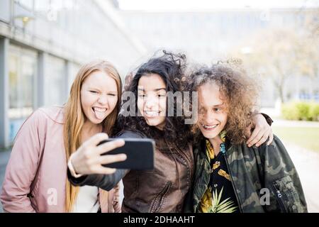 Felice ragazza adolescente che prende selfie con gli amici da smartphone Foto Stock