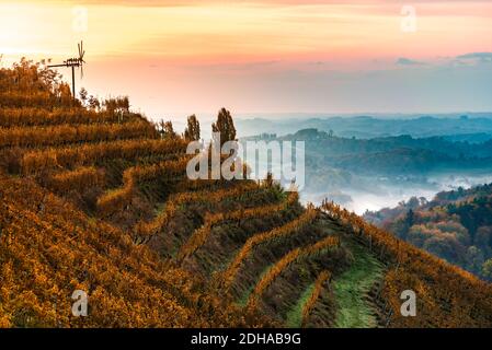 Vista autunnale dalla strada della Stiria meridionale in Austria sulle colline slovene durante il sorgere del sole. Foto Stock