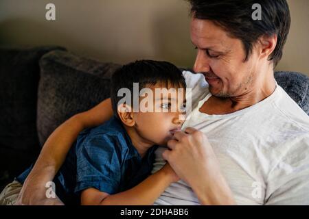 Sorridente padre con figlio seduto sul divano a casa Foto Stock