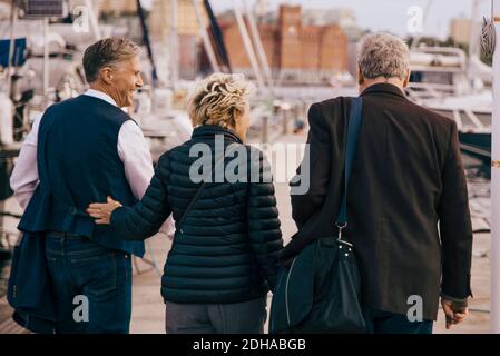 Vista posteriore degli amici anziani con abiti caldi che camminano molo Foto Stock