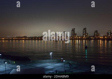 Vista in tempo reale sul Tamigi a Londra con un banca di nebbia dietro alti edifici di appartamenti Foto Stock