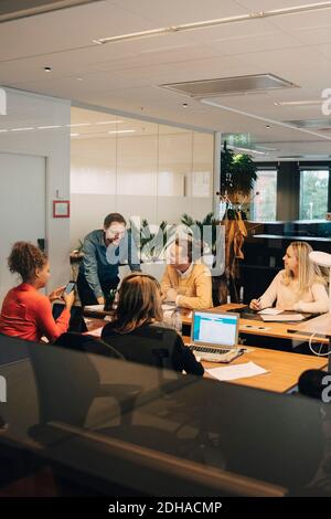 Felici colleghi multietnici che discutono in ufficio Foto Stock