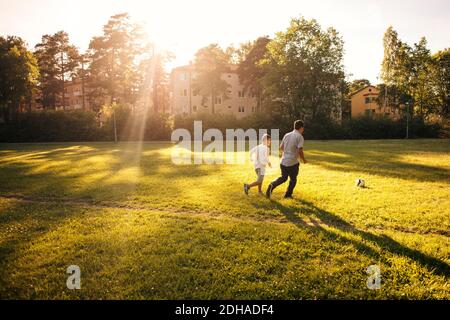 Tutta la lunghezza di padre e figlio che gioca a calcio sulla erba campo durante la giornata di sole Foto Stock