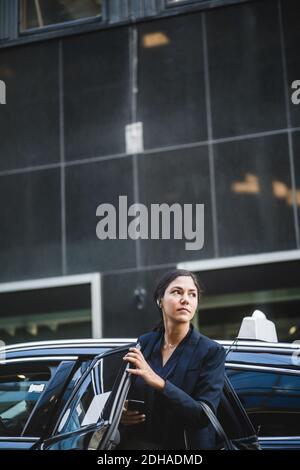 Donna imprenditore che guarda via mentre esce dall'automobile Foto Stock