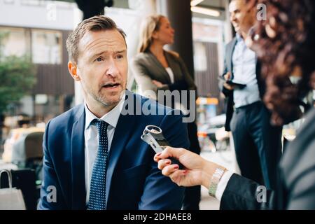 Immagine ritagliata di una donna che intervistava un uomo d'affari in città Foto Stock