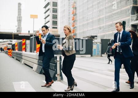 Tutta la lunghezza dei colleghi di affari multietnici che attraversano la strada in città Foto Stock