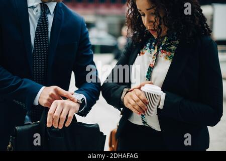 Colleghi di lavoro che guardano il tempo in orologi da polso Foto Stock