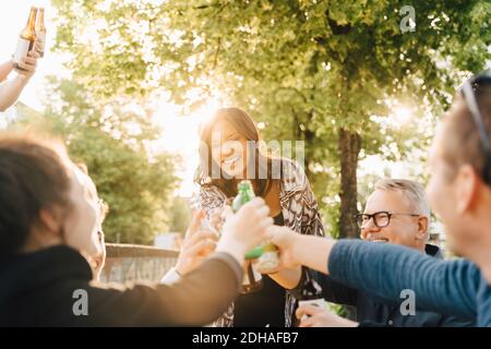 Giovane donna con bevanda in piedi durante la tostatura in riunione sociale Foto Stock