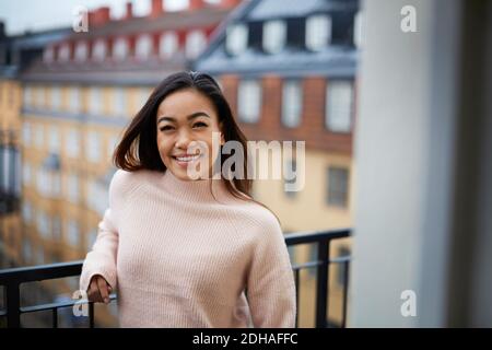Ritratto di felice giovane donna in piedi in balcone Foto Stock